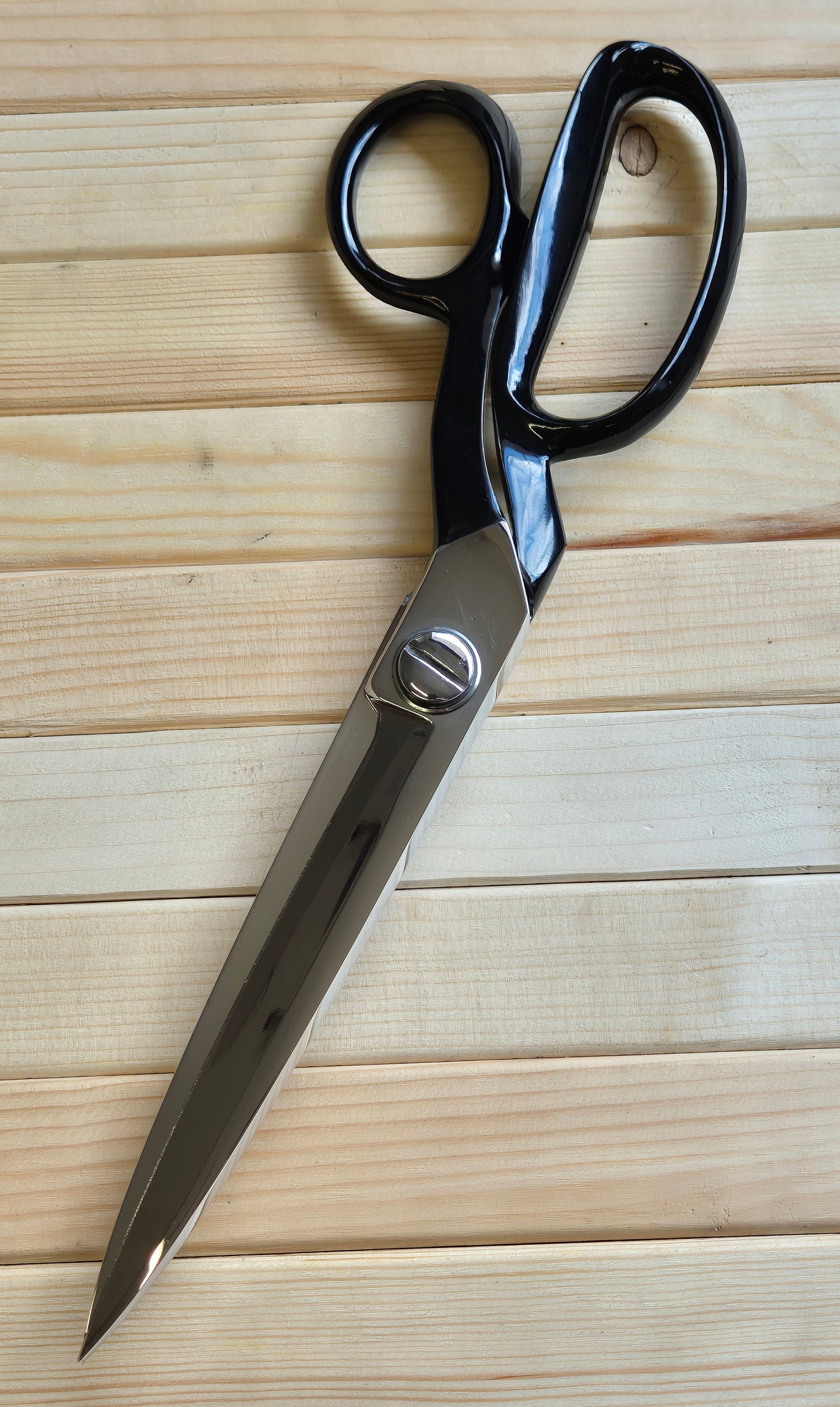 Pair of black-handled scissors on a wooden surface