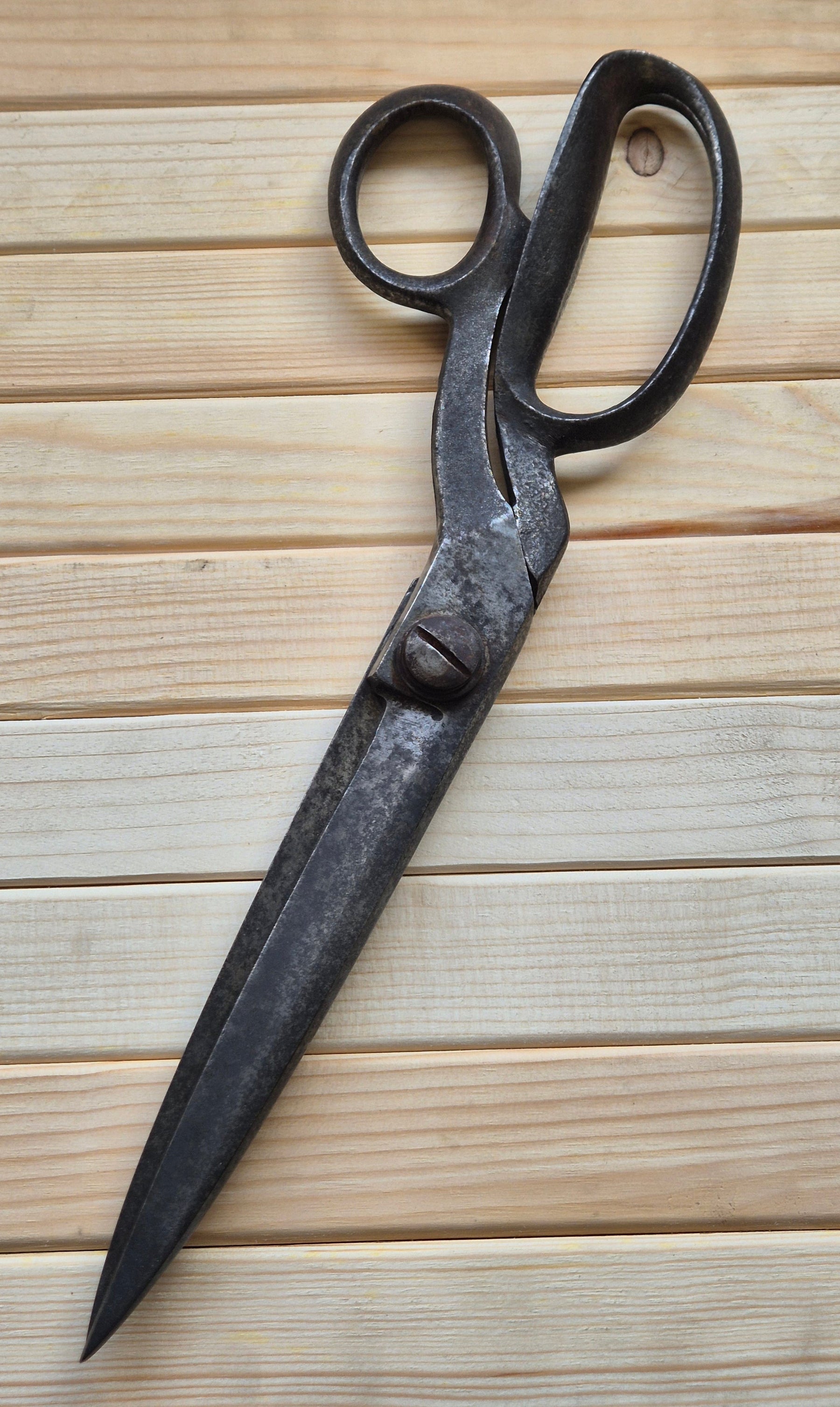 Old-fashioned black shears on a wooden surface